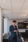 Vue latérale d'un homme d'affaires debout utilisant un téléphone portable dans la salle de conférence au bureau — Photo de stock
