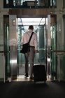 Задній вид бізнесмен з Дорожня сумка заходячи в Ліфт, в офісі — стокове фото