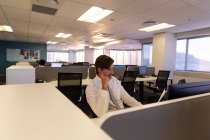 Vista frontal de los jóvenes y reflexivos ejecutivos caucásicos trabajando en el escritorio en una oficina moderna - foto de stock