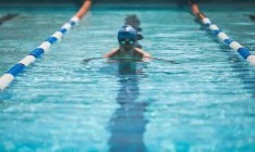 Vista frontale del giovane nuotatore maschio caucasico che nuota colpo di farfalla nella piscina all'aperto sotto il sole — Foto stock