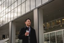 Фронтальний вид молоді азіатські бізнесмен з чашки кави йшов по вулиці в місто — стокове фото