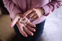 Крупним планом активна старша жінка тримає слуховий апарат в руці вдома — стокове фото