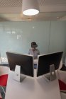 Vue grand angle d'une femme d'affaires asiatique utilisant un casque de réalité virtuelle au bureau — Photo de stock