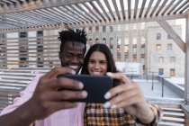 Frontansicht eines multiethnischen Paares, das ein Selfie auf dem heimischen Balkon macht — Stockfoto