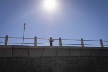 Visão de ângulo baixo de uma mulher idosa ativa fazendo jogging em um passeio sob a luz do sol — Fotografia de Stock