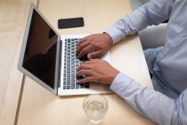 Ansicht eines Geschäftsmannes, der an seinem Laptop arbeitet, während er am Schreibtisch im Büro sitzt — Stockfoto