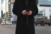 Mid section of young Asian businessman using mobile phone on street — Stock Photo