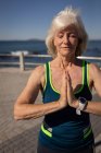 Vue de face d'une femme âgée active effectuant du yoga sur une promenade sous le soleil — Photo de stock