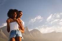 Низкий угол обзора афро-американской пары, стоящей вместе в романтическом настроении рядом с морем — стоковое фото