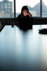 Visão frontal da jovem executiva focada trabalhando no laptop à mesa em um escritório moderno — Fotografia de Stock