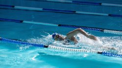 Seitenansicht einer jungen Schwimmerin, die an einem sonnigen Tag im Schwimmbad schwimmt — Stockfoto
