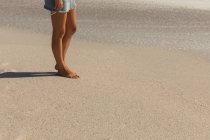 Нижняя часть белой женщины загорела на пляже в солнечный день. Она идет. — стоковое фото
