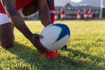 Primo piano di un giovane giocatore di rugby maschile che mette la palla da rugby sul tee calci nello stadio — Foto stock