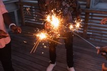 Group of multi ethnic friends enjoying out with sparklers in balcony at home — Stock Photo