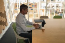 Вид збоку бізнесмена, який працює на ноутбуці і сидить в офісі — стокове фото