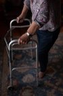 Sezione bassa di una donna anziana attiva che cammina con un deambulatore nel soggiorno di casa — Foto stock