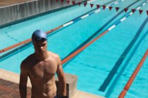 Hochwinkelaufnahme eines jungen kaukasischen männlichen Schwimmers, der an sonnigen Tagen fokussiert im Freibad steht — Stockfoto