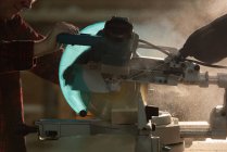 Seitenansicht eines Tischlers, der in der Werkstatt mit einer mechanischen Säge ein Stück Holz schneidet — Stockfoto