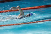 Vista lateral de uma jovem nadadora nadadora nadar livre rastejar na piscina em um dia ensolarado — Fotografia de Stock