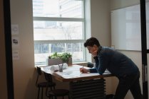 Seitenansicht eines Geschäftsmannes, der auf einer Bürokonferenz steht und an einem Entwurf arbeitet — Stockfoto