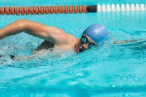Vista laterale ravvicinata del giovane nuotatore maschio caucasico che nuota freestyle nella piscina all'aperto sotto il sole — Foto stock