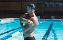 Vista laterale di un giovane nuotatore maschio con maschera da nuoto che si estende in piscina — Foto stock