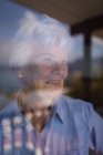 Nahaufnahme einer glücklichen aktiven Seniorin, die zu Hause aus dem Fenster schaut — Stockfoto