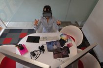 Vista ad alto angolo di una donna d'affari asiatica che utilizza un auricolare di realtà virtuale alla scrivania in ufficio — Foto stock