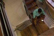 Vista de alto ángulo del hombre de negocios afroamericano usando el teléfono móvil en la escalera en la oficina - foto de stock