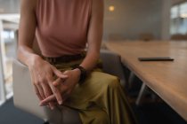 Parte média de uma mulher de negócios sentada no escritório perto de sua mesa — Fotografia de Stock