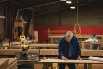 Vorderseite eines kaukasischen Tischlers, der in einer Werkstatt arbeitet — Stockfoto