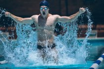 Junge kaukasische Schwimmer mit ausgestreckten Armen feiern Sieg im Pool bei Sonnenschein — Stockfoto