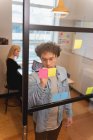 Visão de alto ângulo do empresário caucasiano escrevendo em nota pegajosa no escritório com a mulher caucasiana trabalhando atrás dele — Fotografia de Stock