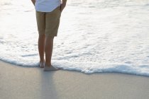 Bassa sezione di uomo rilassato in piedi sulla spiaggia in una giornata di sole. Si sta godendo la sua vacanza — Foto stock