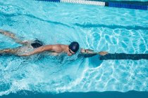 Vista de alto ângulo do jovem nadador masculino caucasiano nadador livre na piscina ao ar livre ao sol — Fotografia de Stock