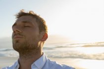 Nahaufnahme eines gutaussehenden Mannes, der sich an einem sonnigen Tag am Strand entspannt. Er genießt seinen Urlaub — Stockfoto