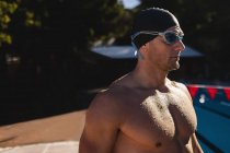 Side view of a Caucasian male swimmer with swim goggle standing near the swimming pool — Stock Photo