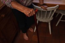 Низкая часть активной пожилой женщины, идущей с тростью на кухне дома — стоковое фото