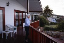 Seitenansicht einer nachdenklichen aktiven Seniorin, die auf einem Balkon steht und zu Hause wegschaut — Stockfoto