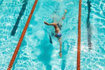 Vista ad alto angolo del giovane nuotatore maschio caucasico che nuota freestyle in piscina nella giornata di sole — Foto stock
