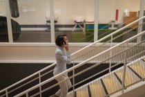 Вид збоку азіатських підприємець говорити на її мобільний телефон під час сходження по сходах — стокове фото