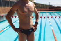 Розділ середині чоловічого плавець з руки на стегна стоять перед відкритий плавальний басейн на сонячний день — стокове фото