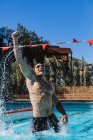 Вид спереду збудженого чоловічого плавця, який святкує свою перемогу і піднімає кулак у басейні — стокове фото