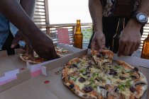 Milieu de la section du groupe d'amis profiter de pizza partie dans le balcon à la maison — Photo de stock