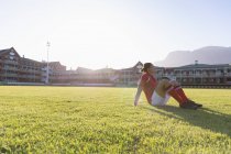 Vista lateral de um jogador de rugby caucasiano sentado no estádio em um dia ensolarado — Fotografia de Stock