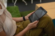 Vue en angle élevé d'une femme d'affaires tenant une tablette numérique alors qu'elle était assise au bureau — Photo de stock