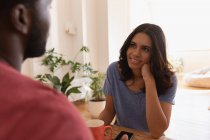 Front view of mixed race couple sitting and talking with each other at home — Stock Photo