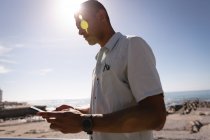 Visão de baixo ângulo do homem usando telefone celular na praia no dia ensolarado — Fotografia de Stock
