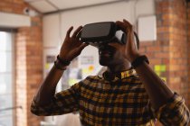 Vue de face d'un homme d'affaires afro-américain utilisant un casque de réalité virtuelle au bureau — Photo de stock