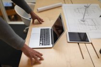 Parte média de um homem de negócios inclinado sobre a mesa e olhando para seu laptop — Fotografia de Stock